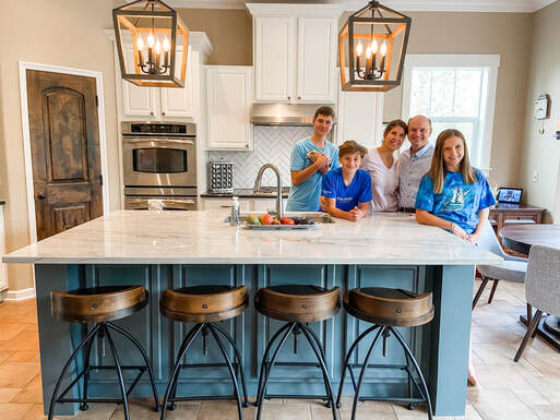 Happy Bloom client in their newly remodeled kitchen. white cabinets. blue island. Bright. Modern.